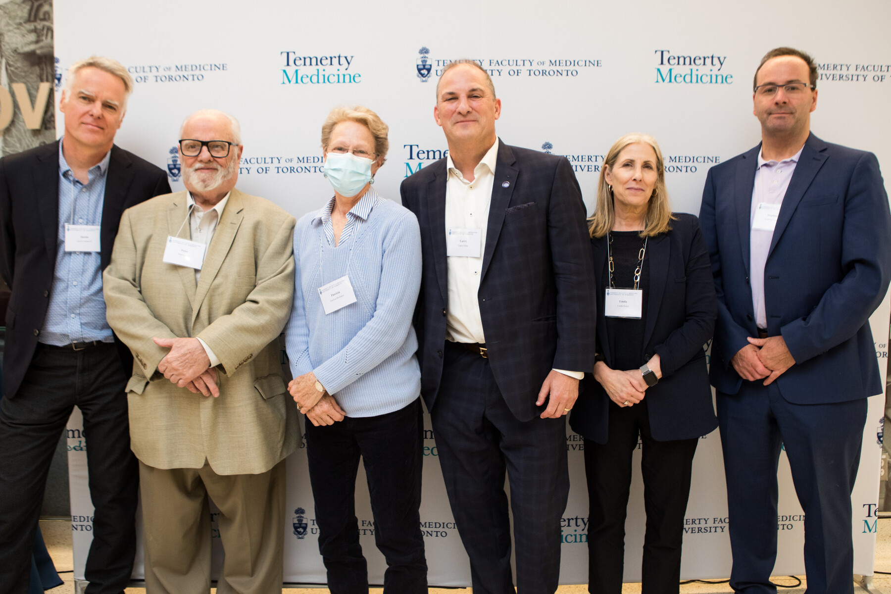 Group photo of six people standing in front of Temerty Faculty of Medicine branded backdrop