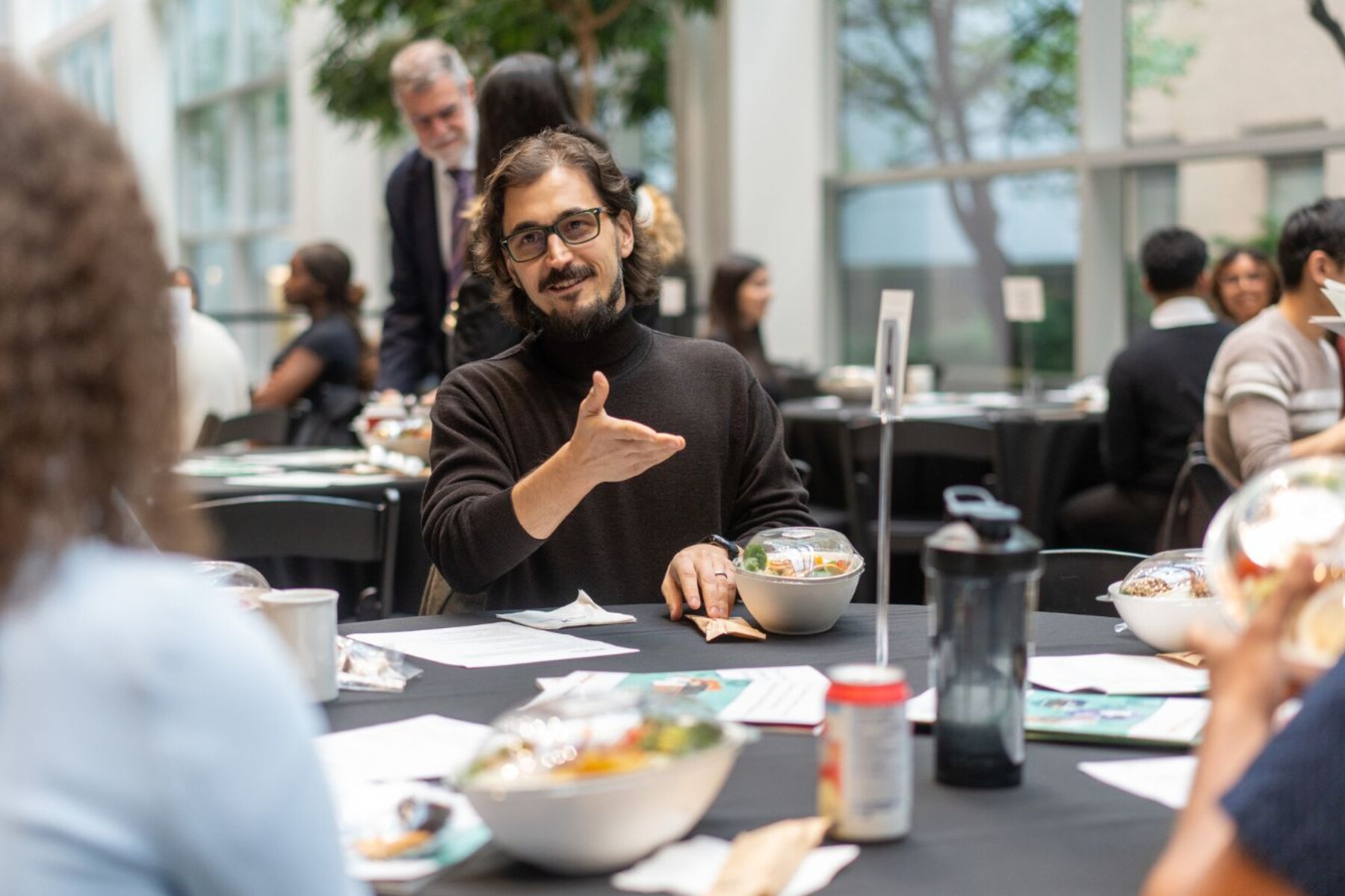 Artem Babaian gesturing while speaking to a student while sitting at a round table for lunch