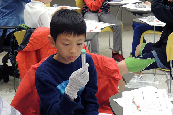 boy holding a research vial during visit to the Centre