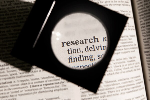 Magnifying glass over the word "research" on a dictionary page