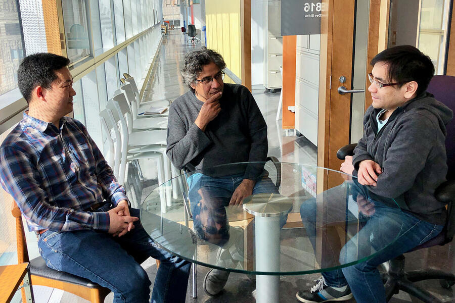 Three researchers sitting around a table discussing science