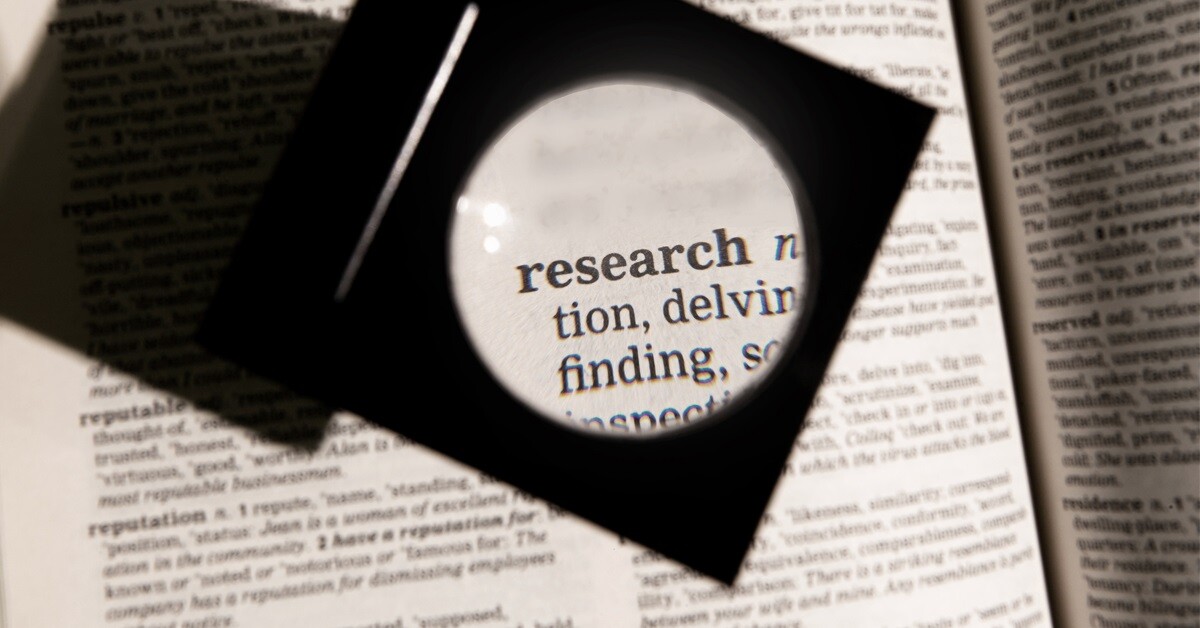 Magnifying glass over the word "research" on a dictionary page