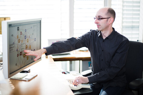 Researcher pointing at data on computer screen